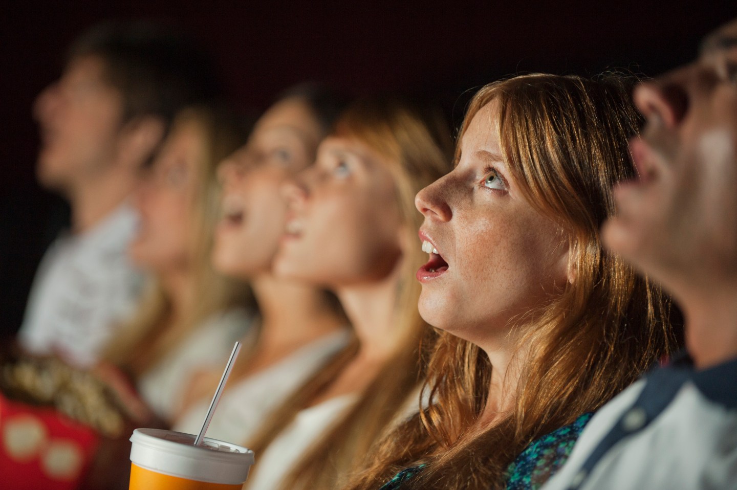 Woman watching movie in theater with shocked expression