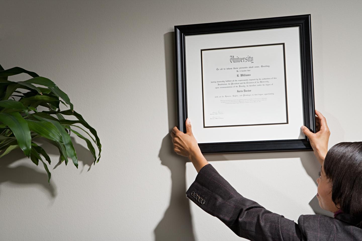 Businesswoman hanging framed certificate