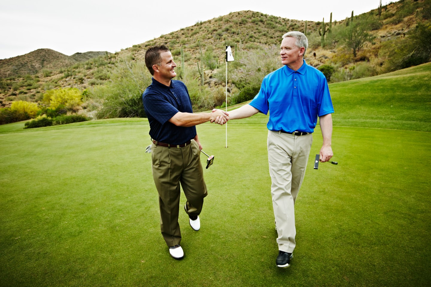 Two golfers walking off green shaking hands