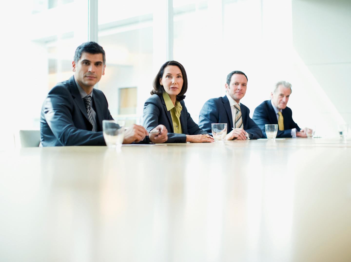 Business people sitting in a row at conference table