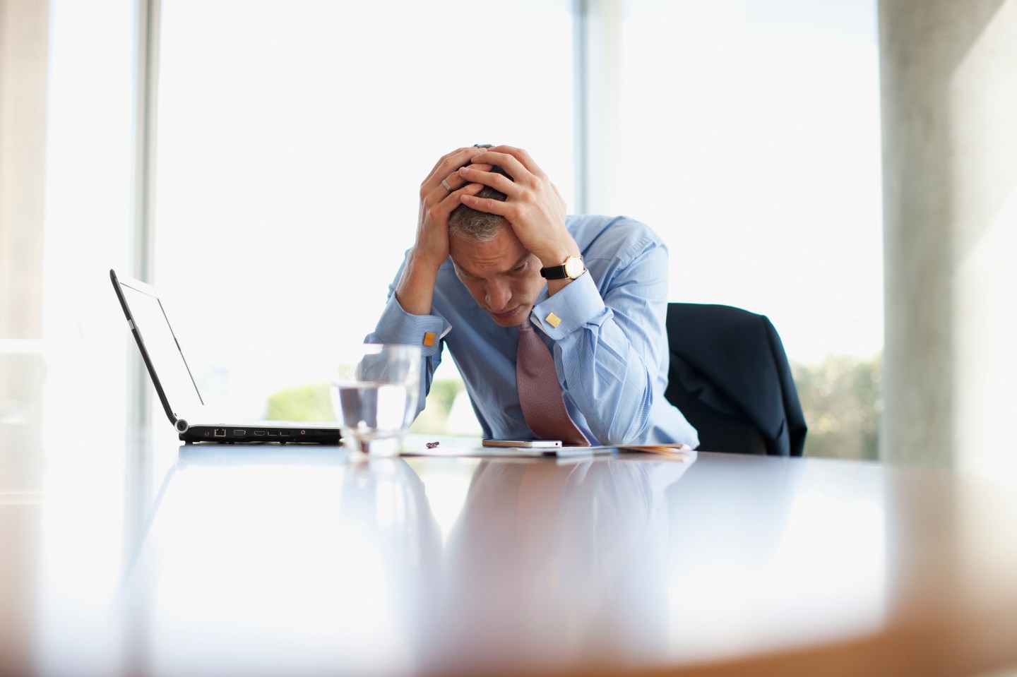 Frustrated businessman with head in hands at desk