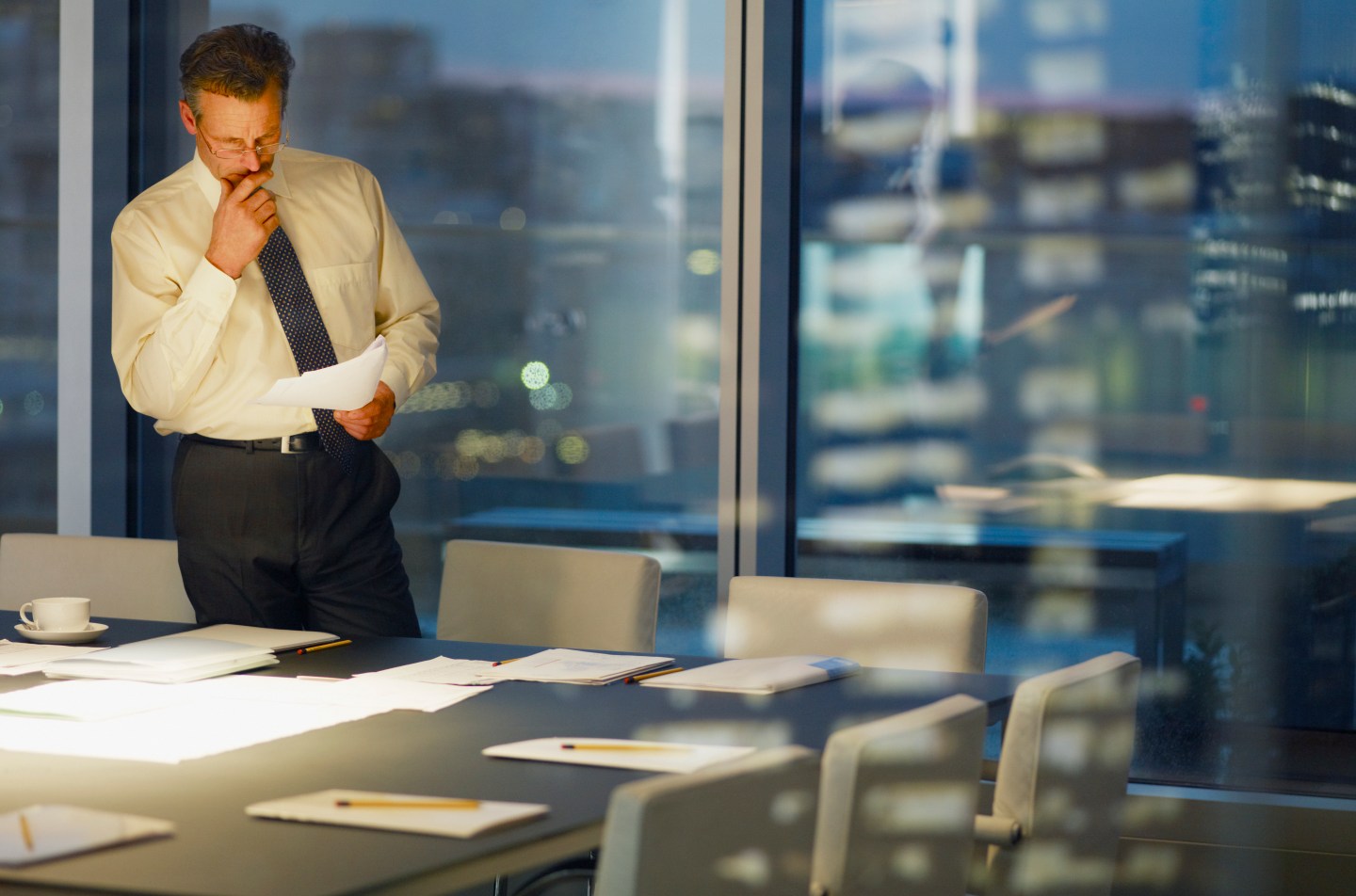 Businessman standing at conference room table at night