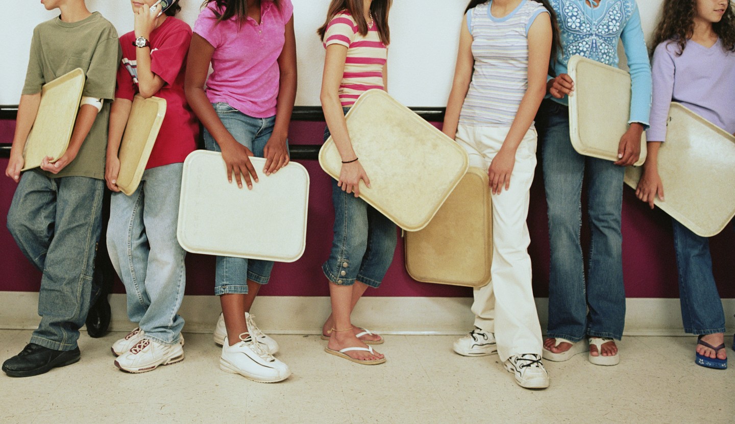 Group of kids (12-14) holding trays on lunch line