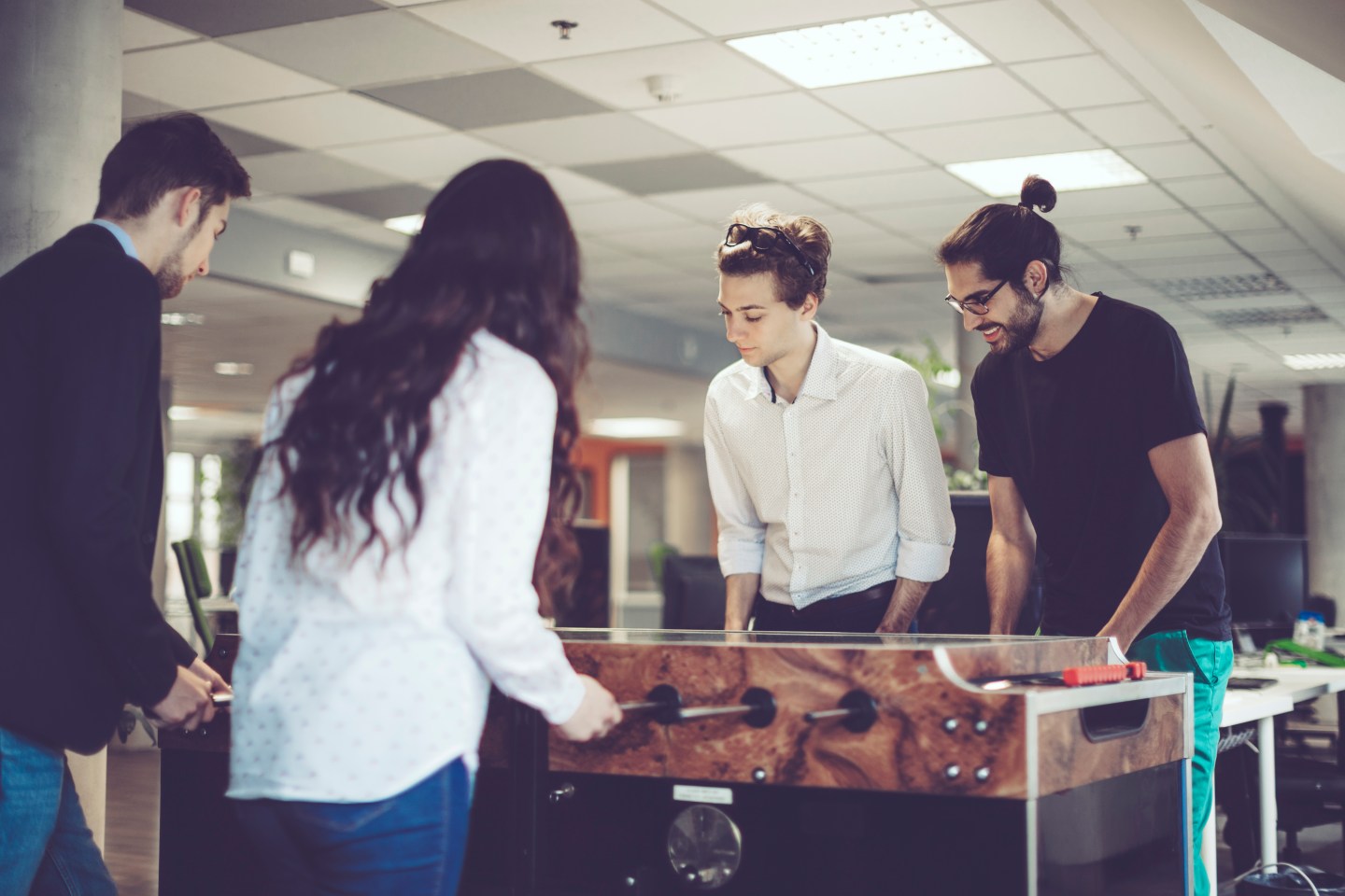 Young adults are playing foosball at work