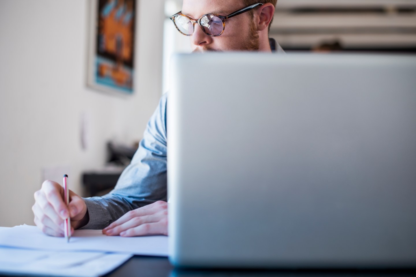 Businessman writing notes at laptop desk