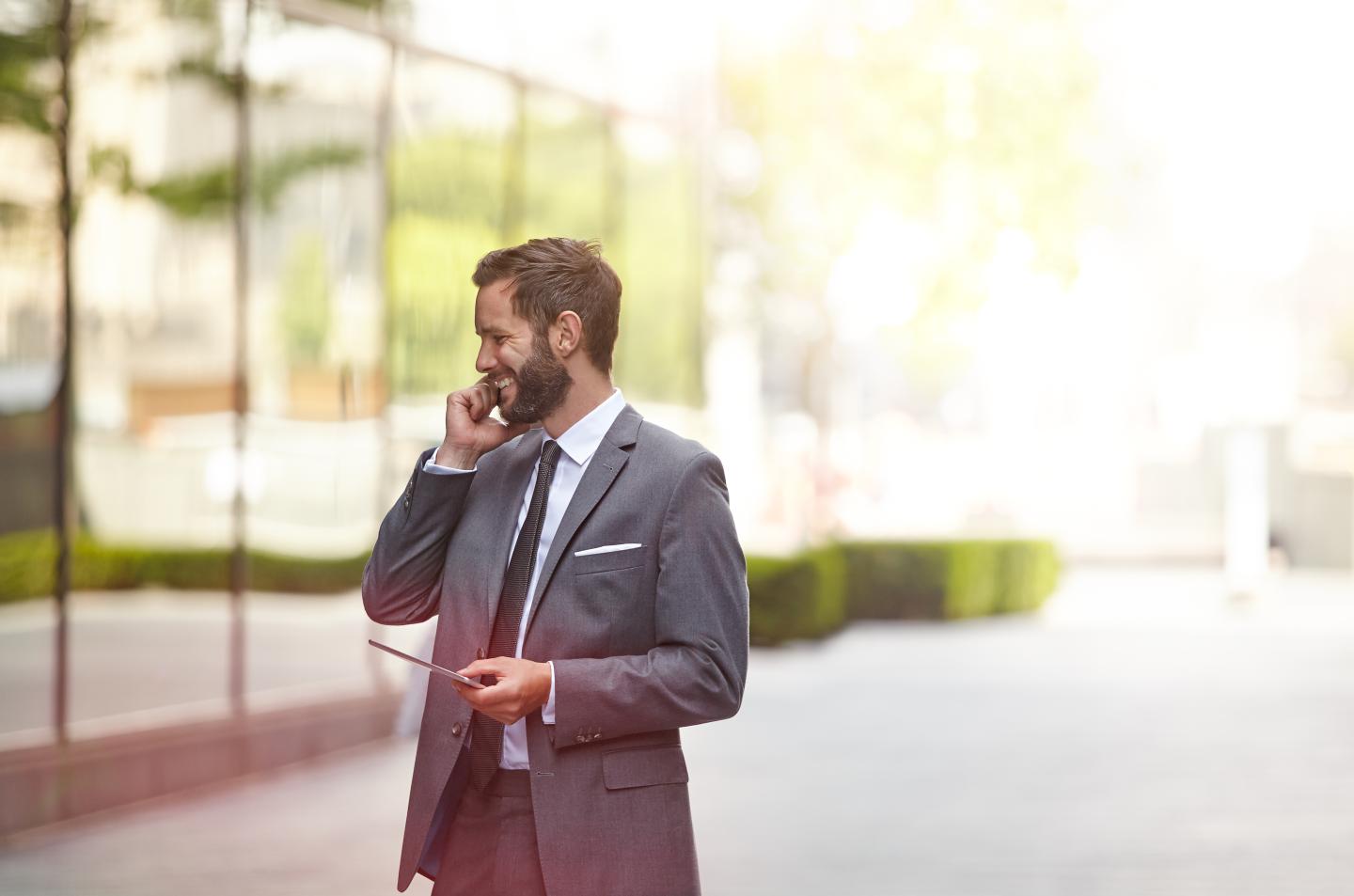 A businessman outside on the phone smiling