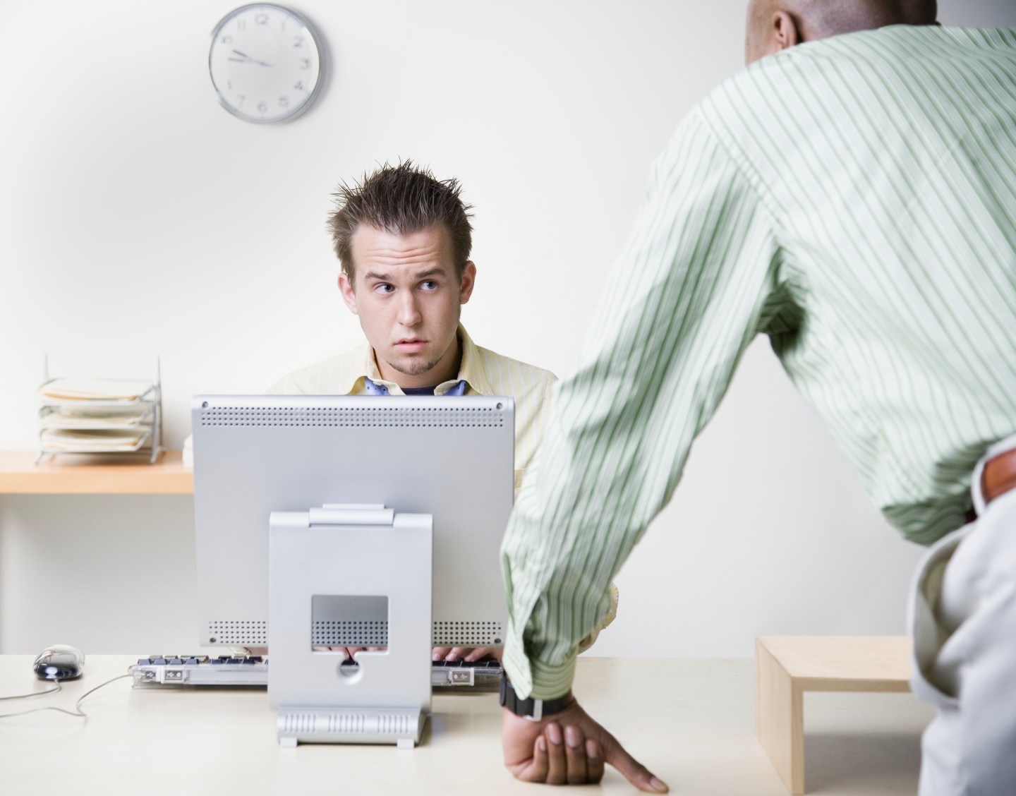 Businessman leaning on desk talking to coworker