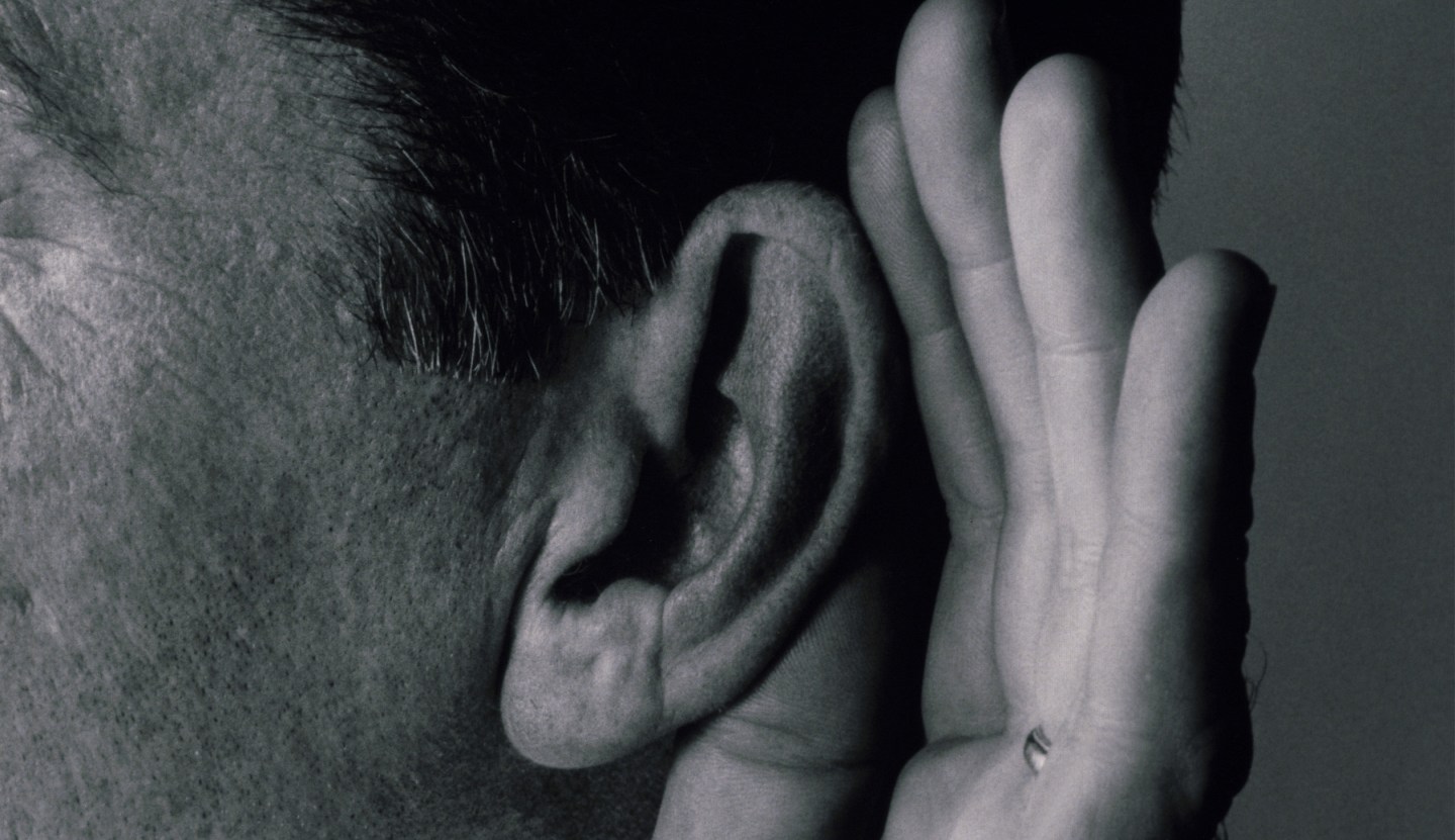 Close-up of a mature man with a cupped hand to his ear