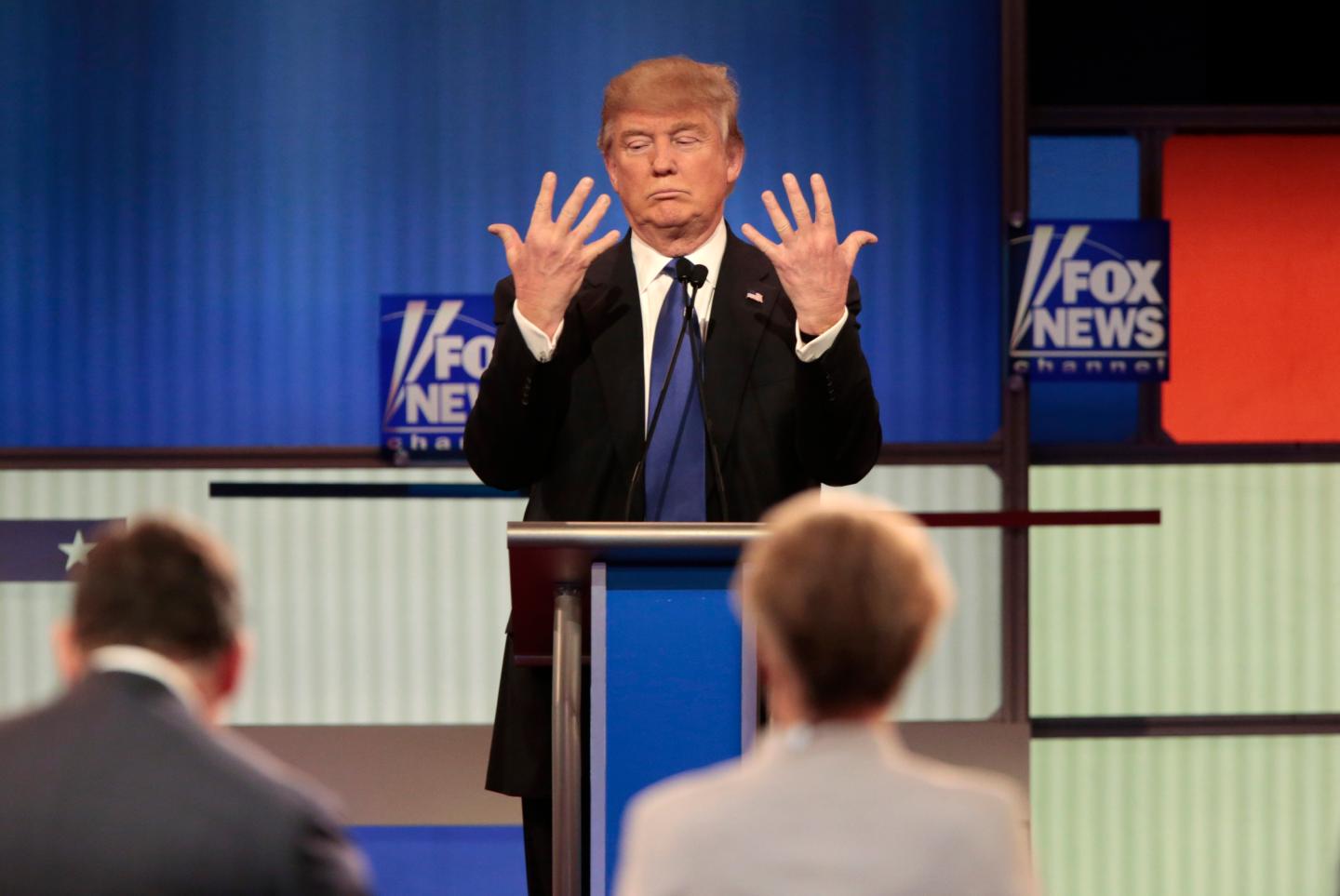 Republican U.S. presidential candidate Trump shows off the size of his hands as Fox News Channel moderators Baier and Kelly look on at the U.S. Republican presidential candidates debate in Detroit