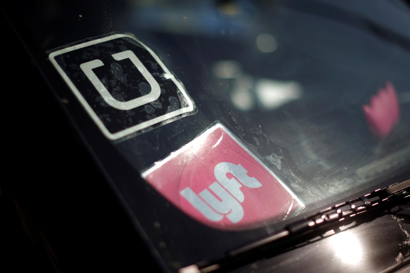 A driver displays Uber and Lyft ride sharing signs on his car windscreen in Santa Monica
