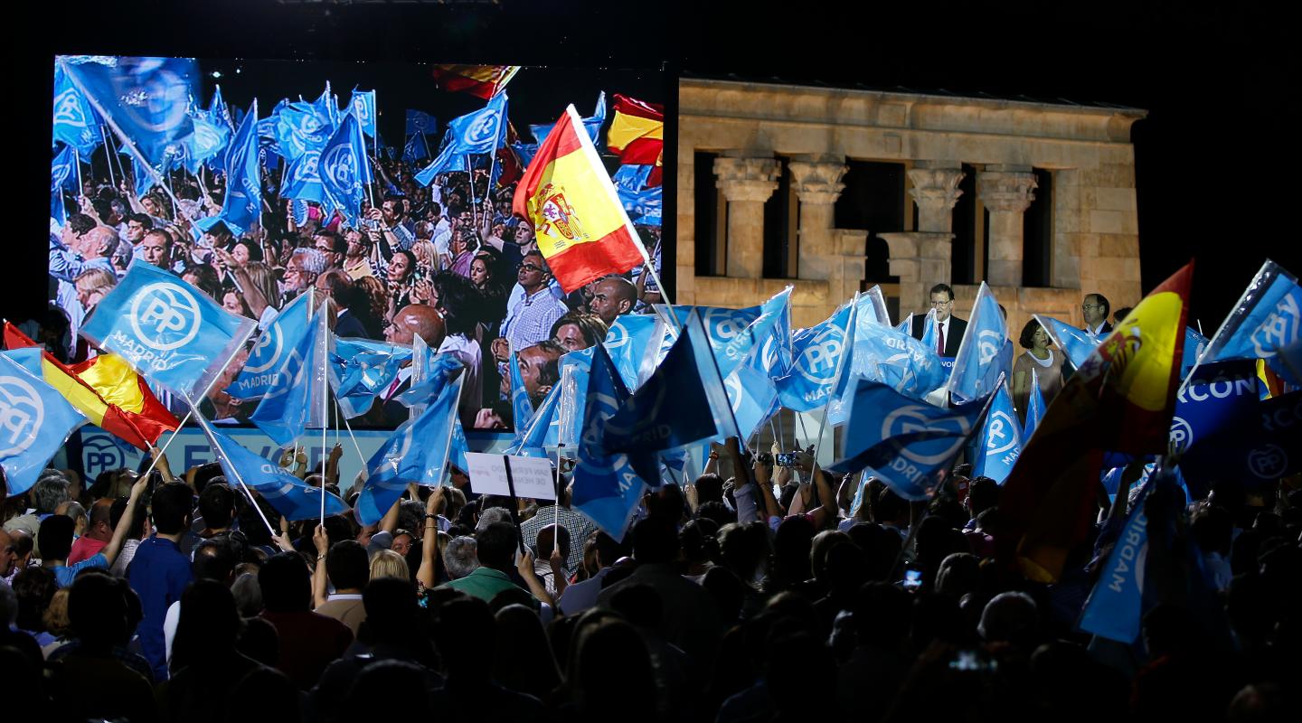 Supporters wave flags as People's Party (PP) leader Mariano Rajoy delivers a speech during a rally at the start of the official campaign period for Spain's general election in Madrid