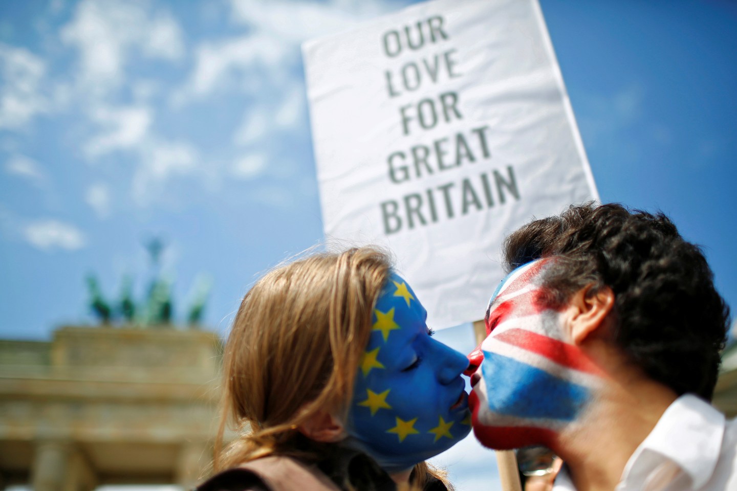 Two activists with the EU flag and Union Jack painted on their faces kiss each other in front of Brandenburg Gate to protest against Brexit in Berlin