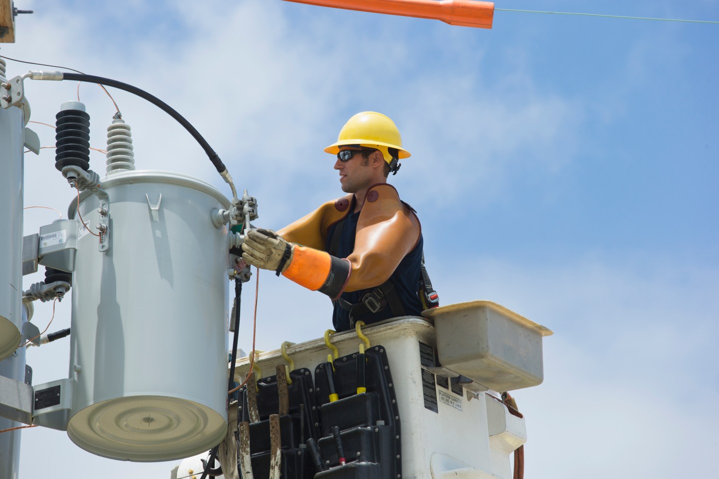 Caucasian worker in cherry picker repairing power line