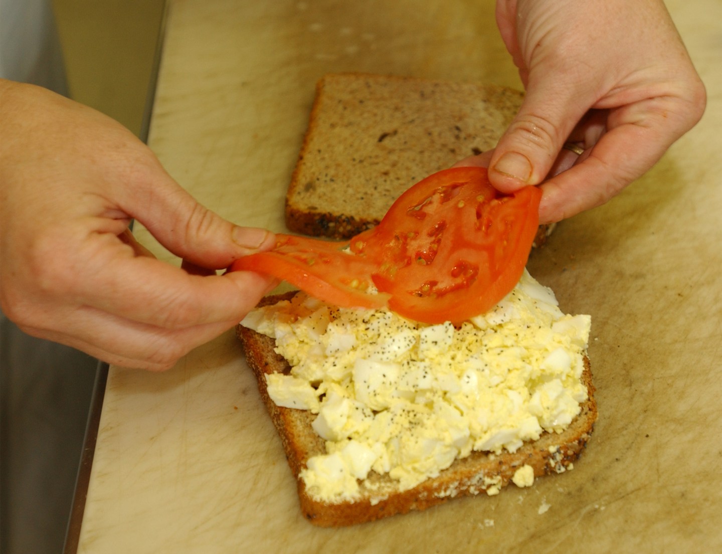 Simone Ryle, owner of Dantes in One city Center lays a couple of tomato slices on an egg salad sandw
