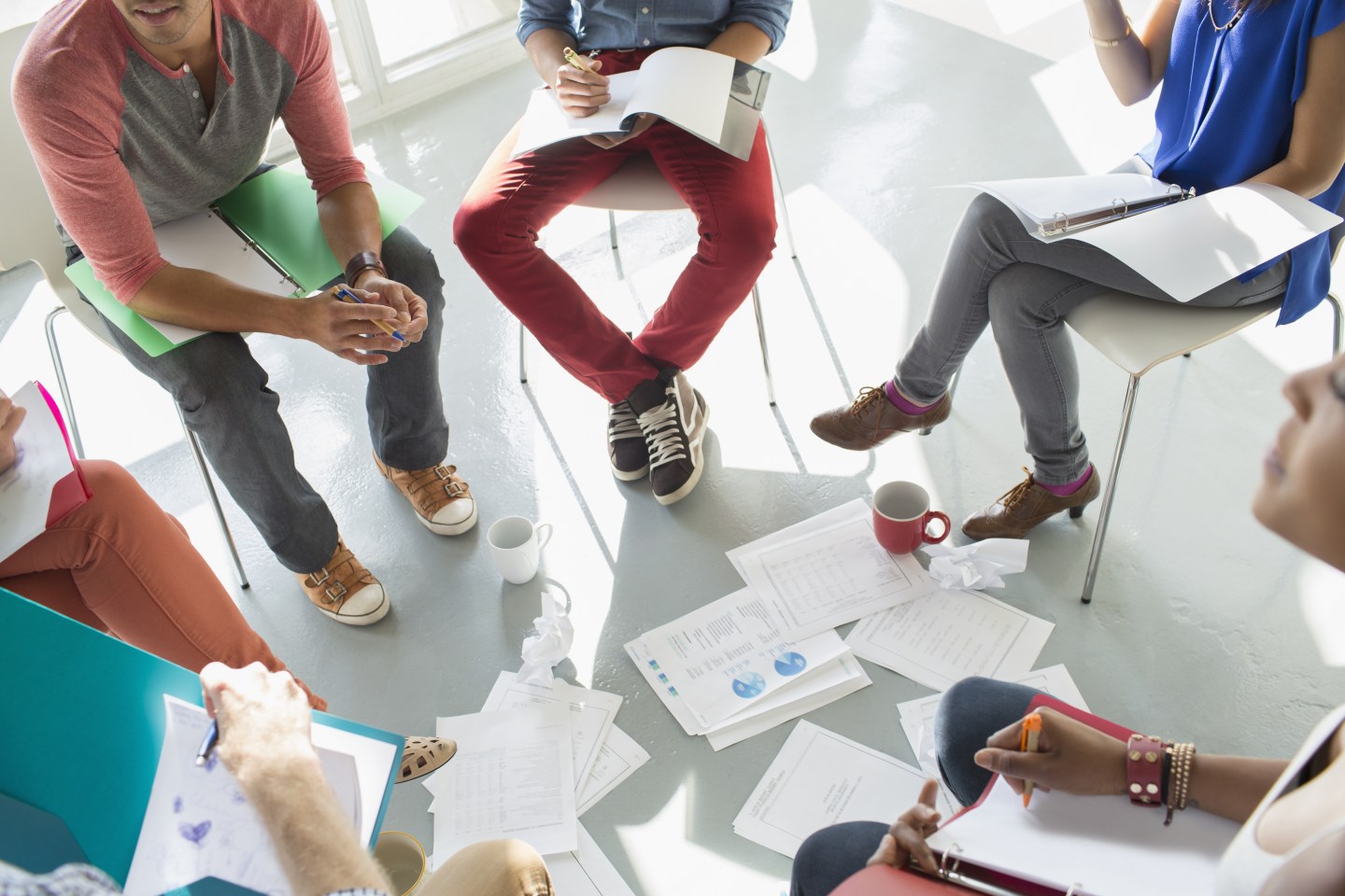 Creative business people meeting with coffee and paperwork in circle of chairs