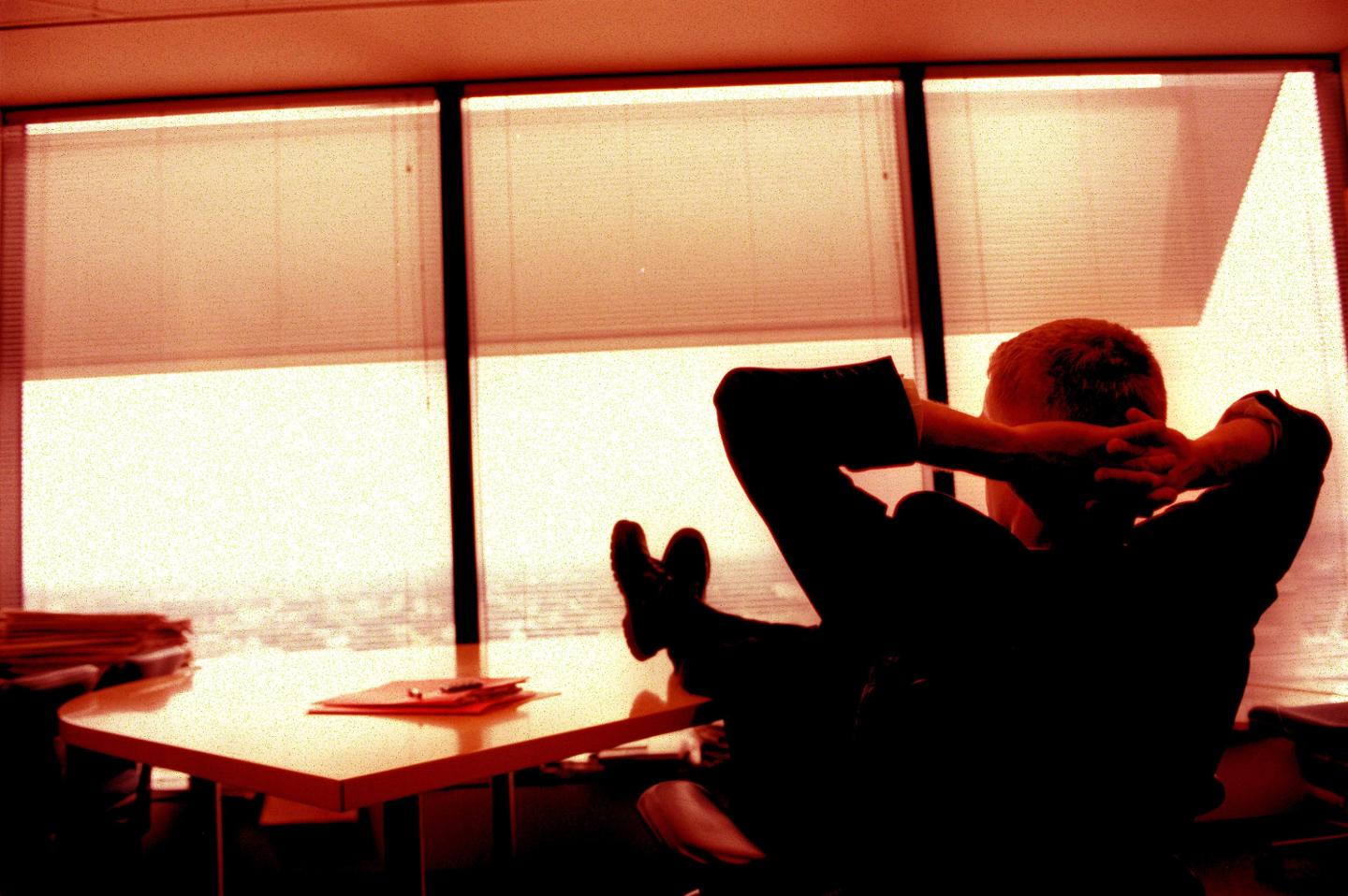 Generic businessman sitting at his desk with his feet up looking out of his exec