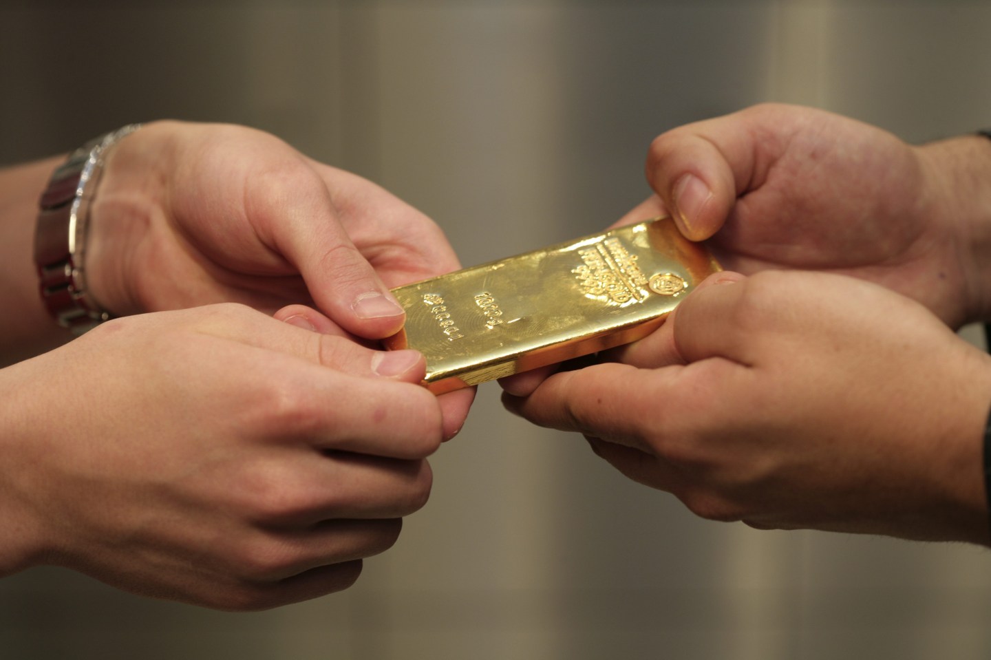 GERMANY, Munich, pro aurum gold house Munich: Seller and buyer hand with 1000g gold bullion (999,9 fine gold) in the vault.