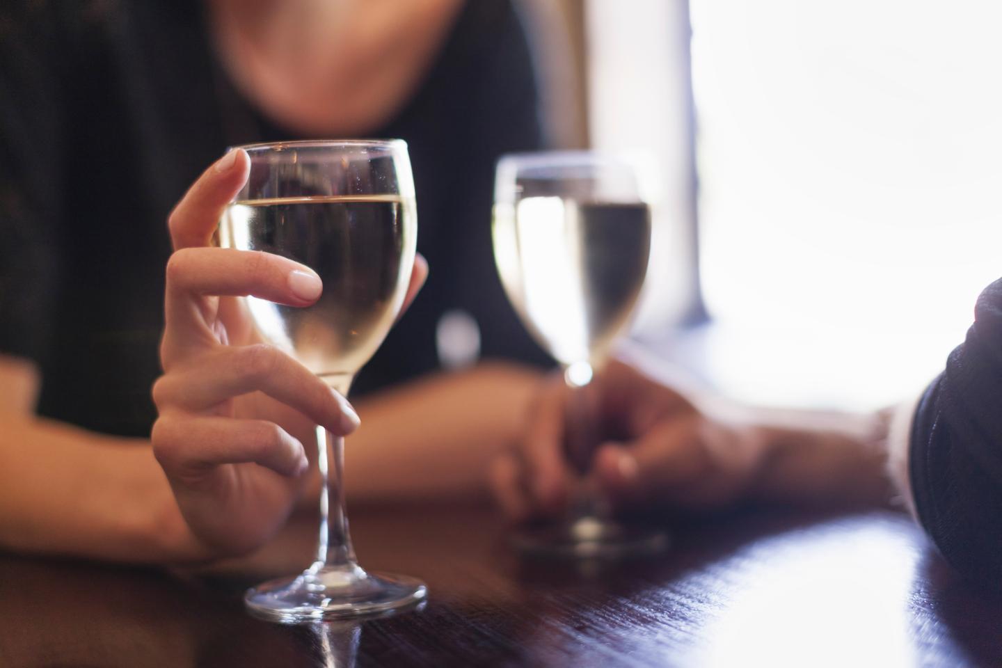 Two people, a couple sitting in a bar having a glass of chilled white wine.