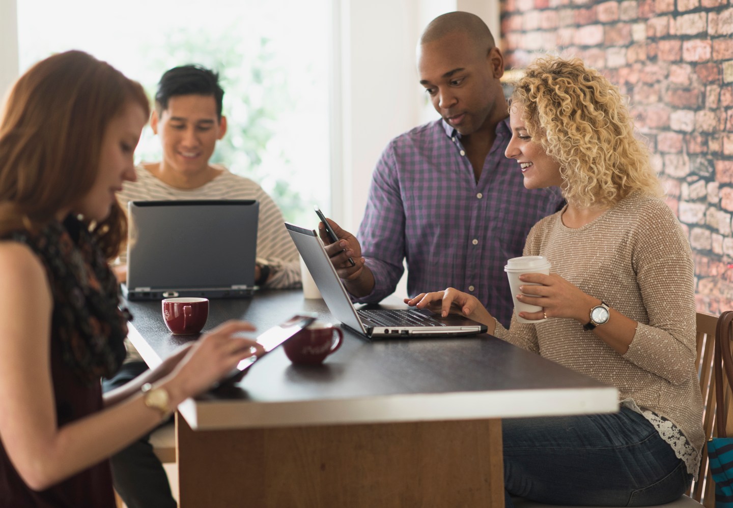 USA, New Jersey, Friends sitting in cafe, using laptops and digital tablets