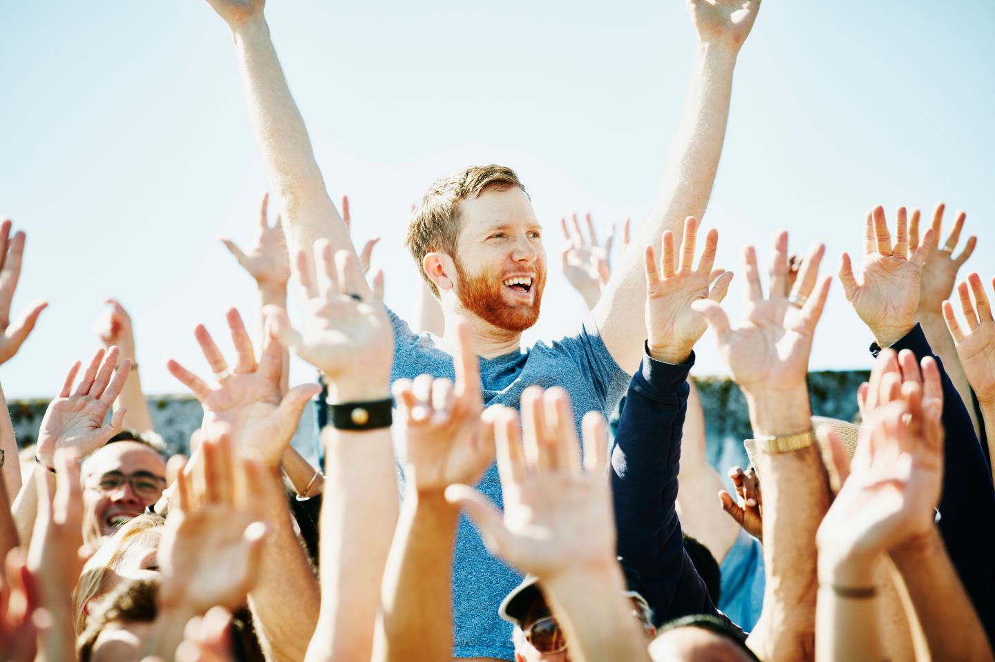 Man cheering in crowd with arms raised