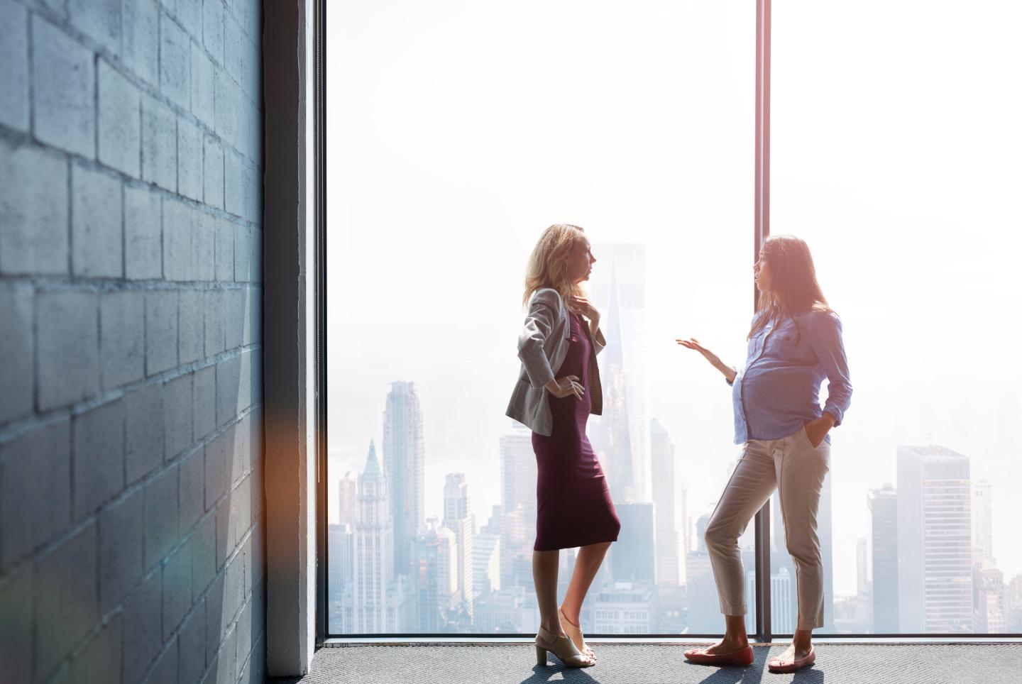 Pregnant woman talking with co-worker