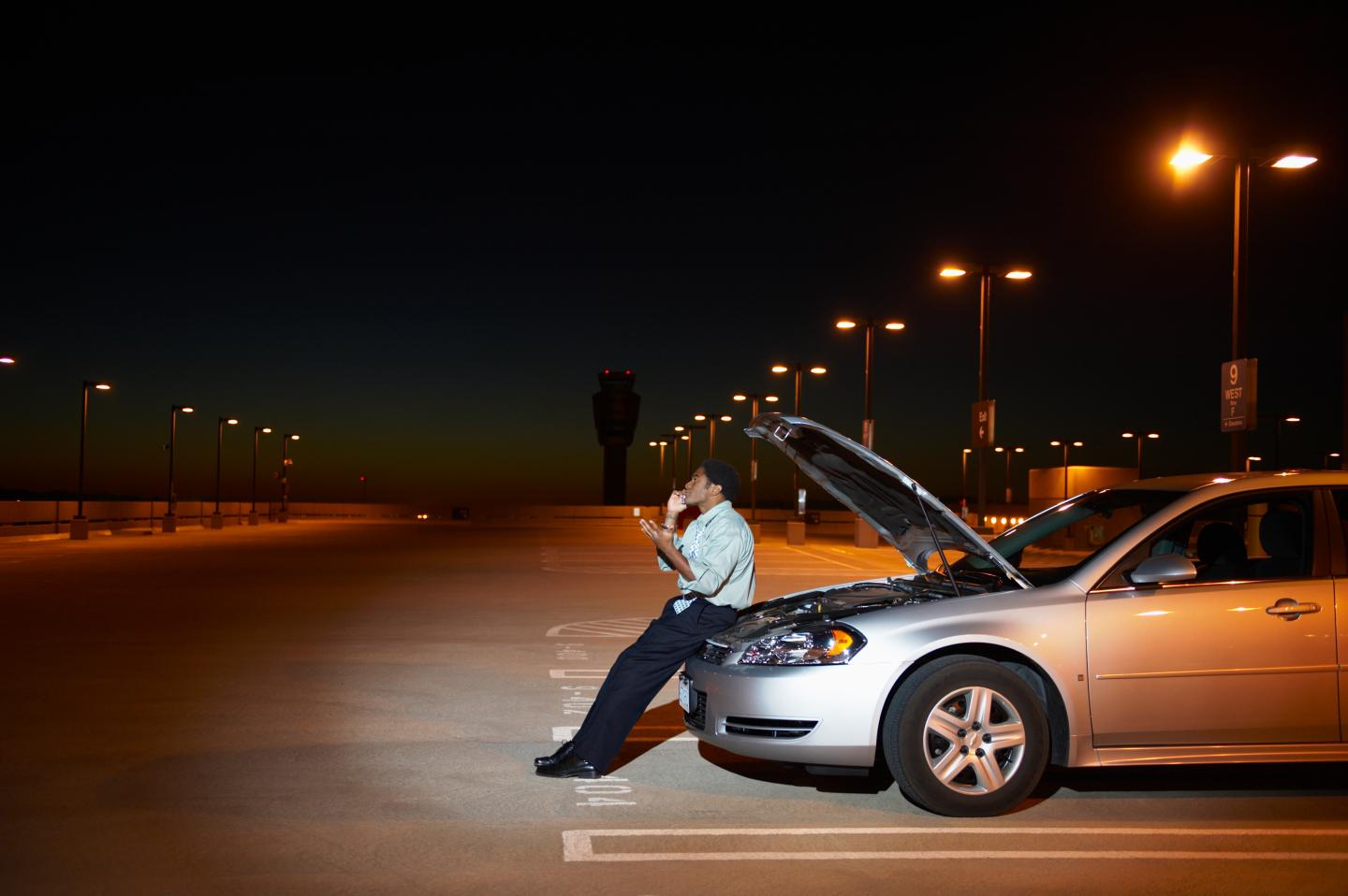African businessman having car trouble in parking lot
