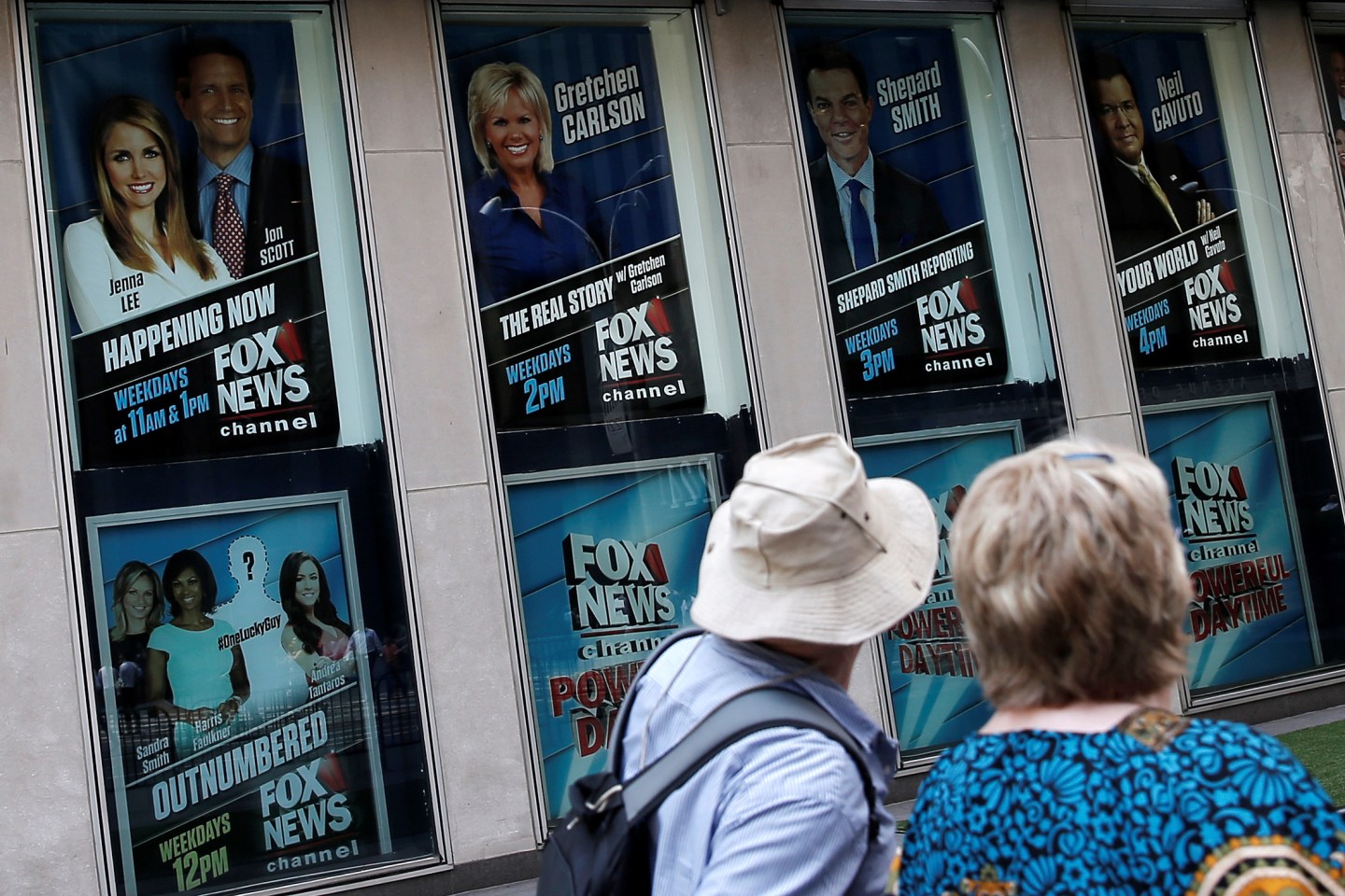 People walk by posters of Fox News personalities including Gretchen Carlson at the News Corporation headquarters building in Manhattan