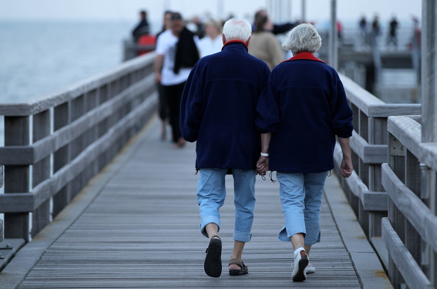 An elderly couple walks on a pier near the Baltic Sea in Germany.