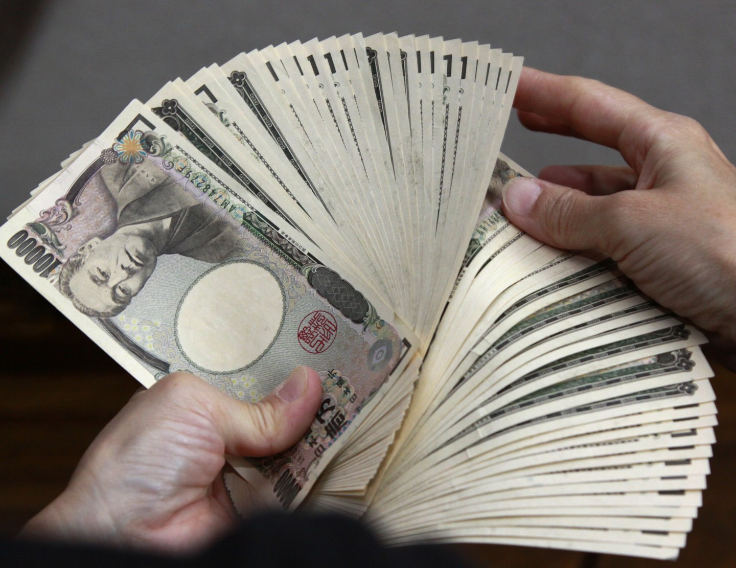 A bank teller counts 10,000 yen (118 USD