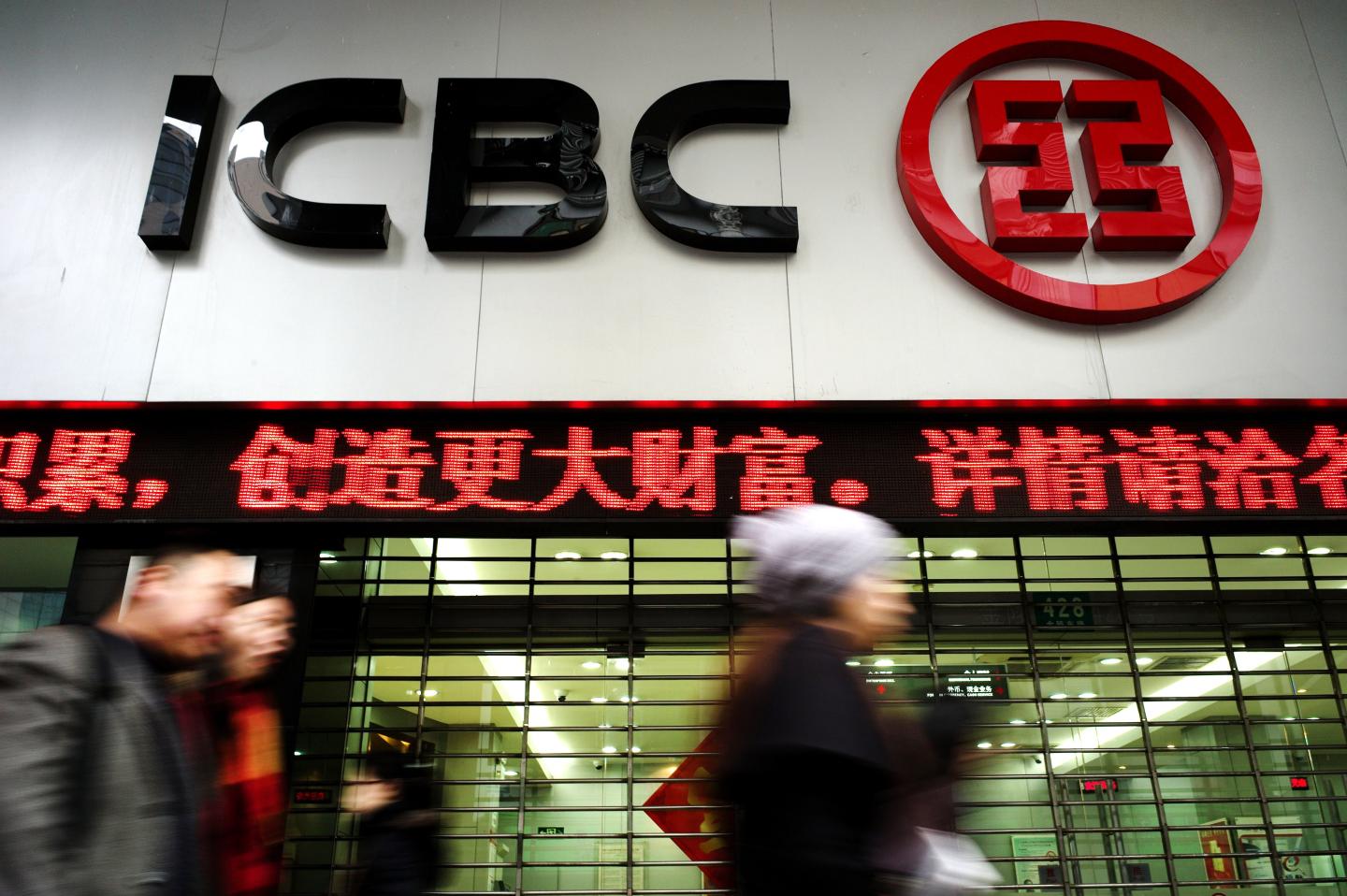 Pedestrians walk past a branch of China'