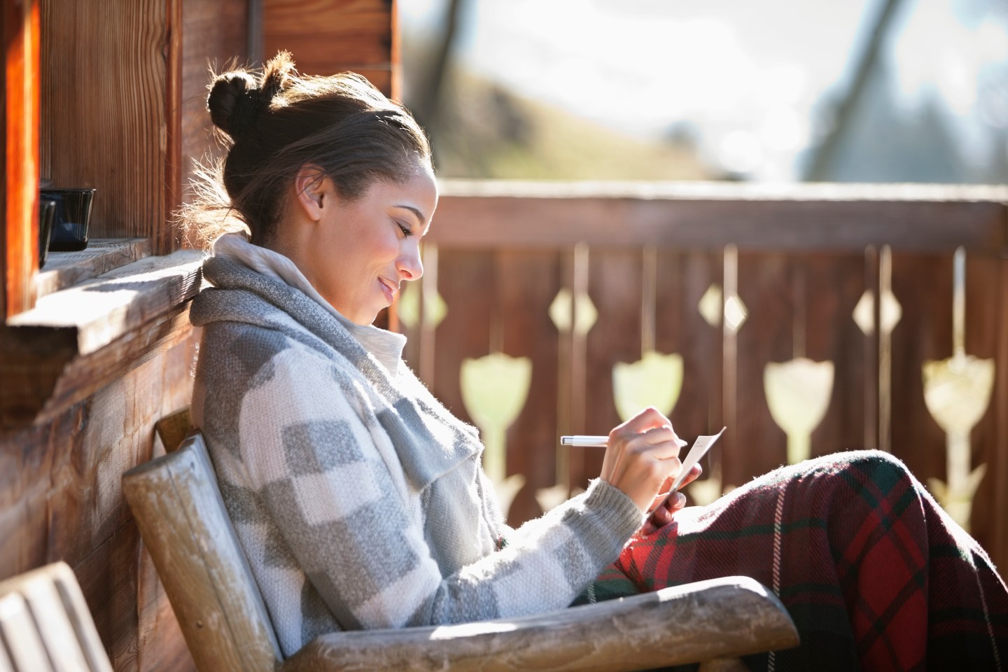 Smiling woman with paper and pen on cabin porch