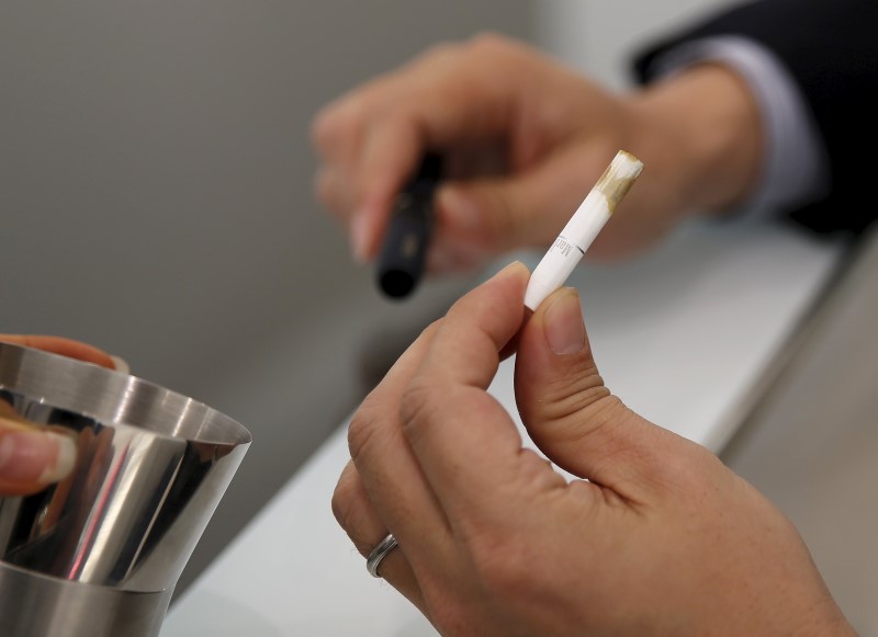 A customer takes off a filter after trying a Philip Morris' "iQOS" smokeless tobacco at an iQOS store in Tokyo