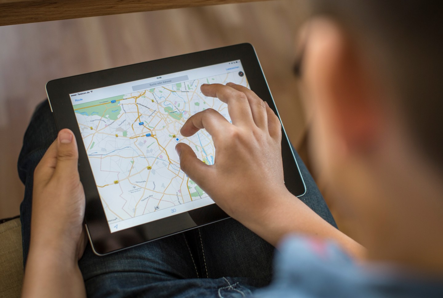 Boy holding an iPad on which Google Maps is opened.