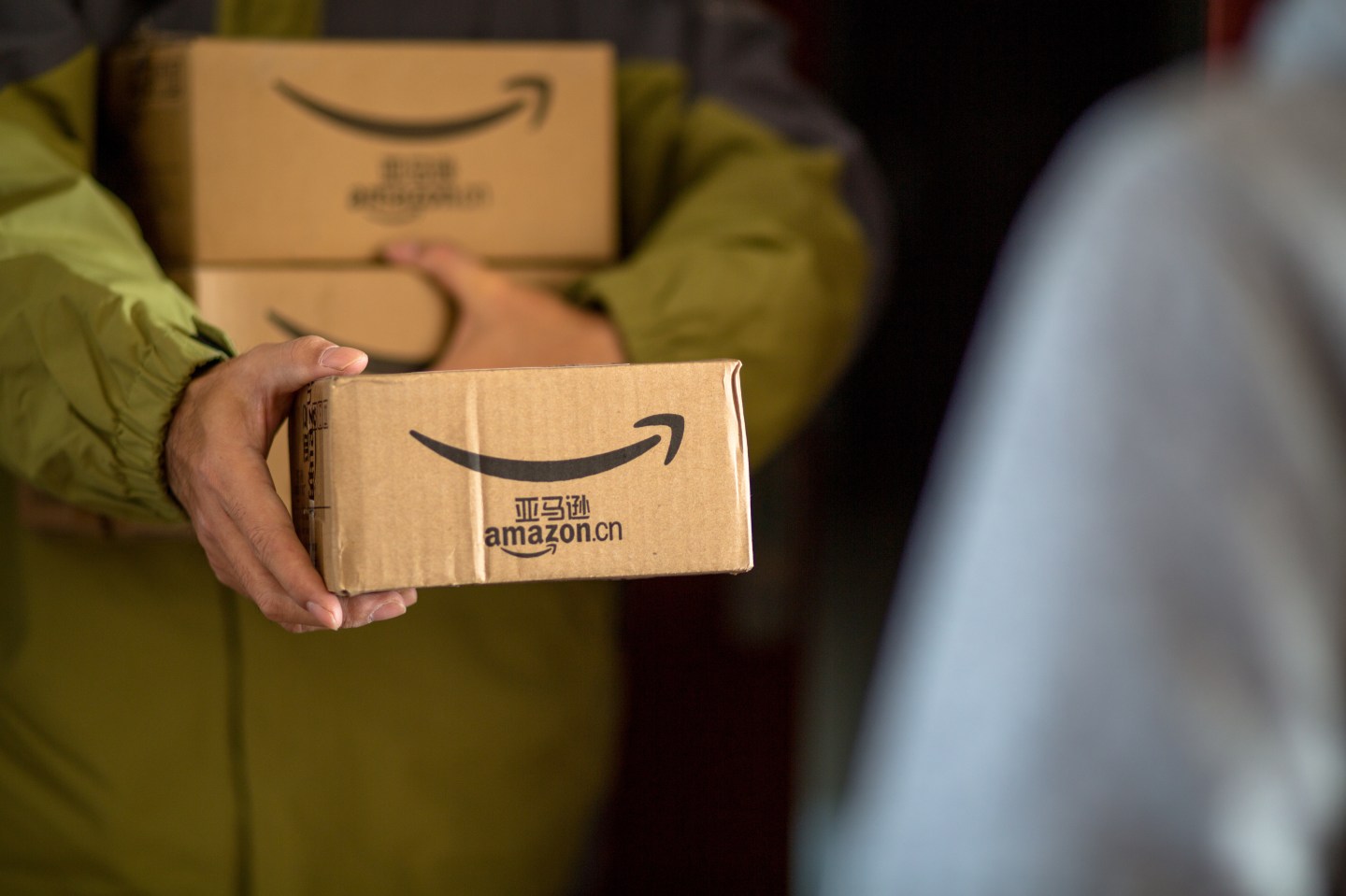 A delivery staff of Amazon.cn sends goods to a customer.