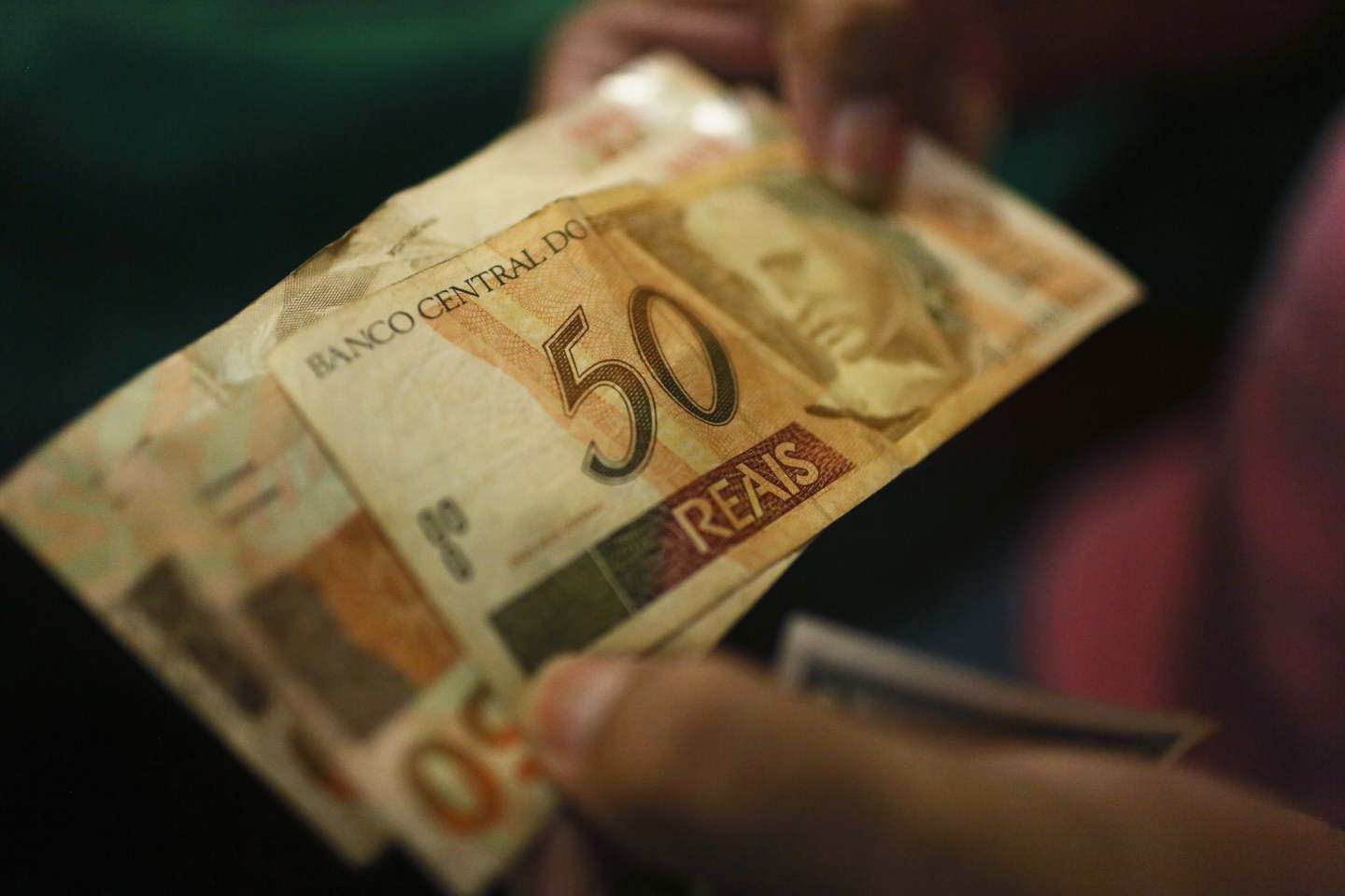 A money changer holds reais, the Brazilian currency, in Rio de Janeiro.