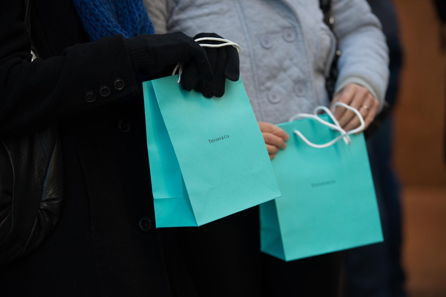 Customers carry Tiffany &amp; Co. shopping bags outside the company's flagship store in New York.
