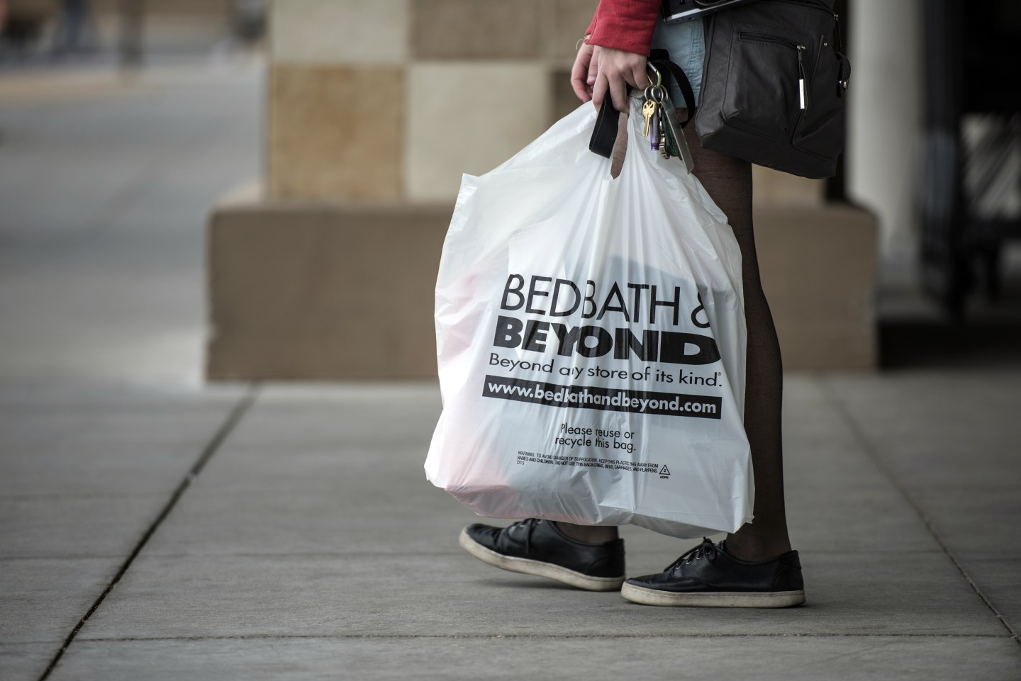 A woman carries a Bed, Bath and Beyond shopping bag as she exits a store in Albuquerque.