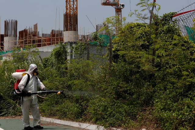 Workers from the Food and Environmental Hygiene Department kill mosquitoes outside a construction site near a residential area in Hong Kong