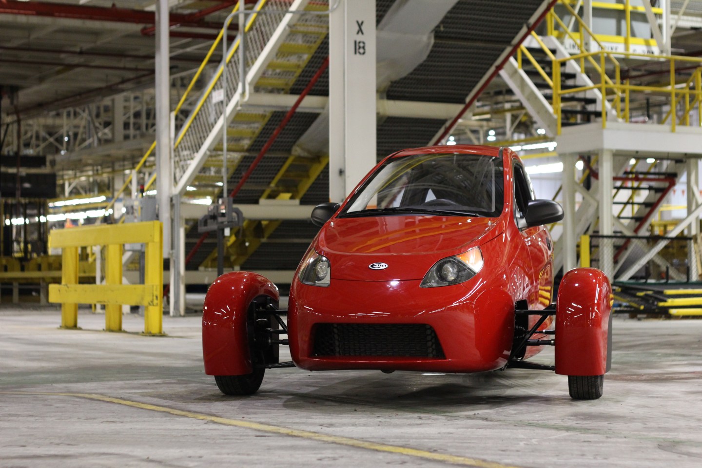 microcar Elio P5, red with three wheels, on factory floor.