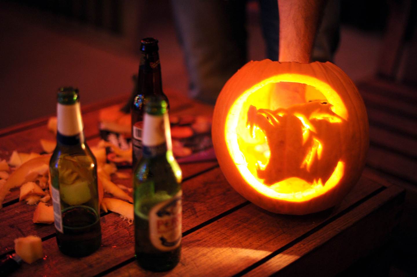 A warewolf carved on a pumpkin next to t