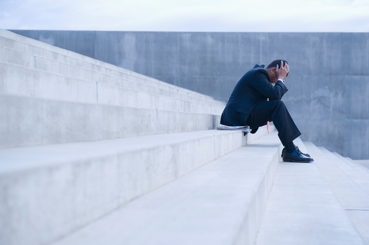 Frustrated Hispanic businessman sitting on steps