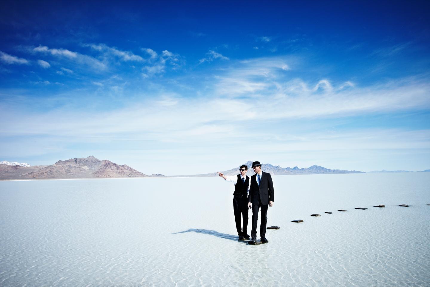 Businessmen standing at end of pathway in lake