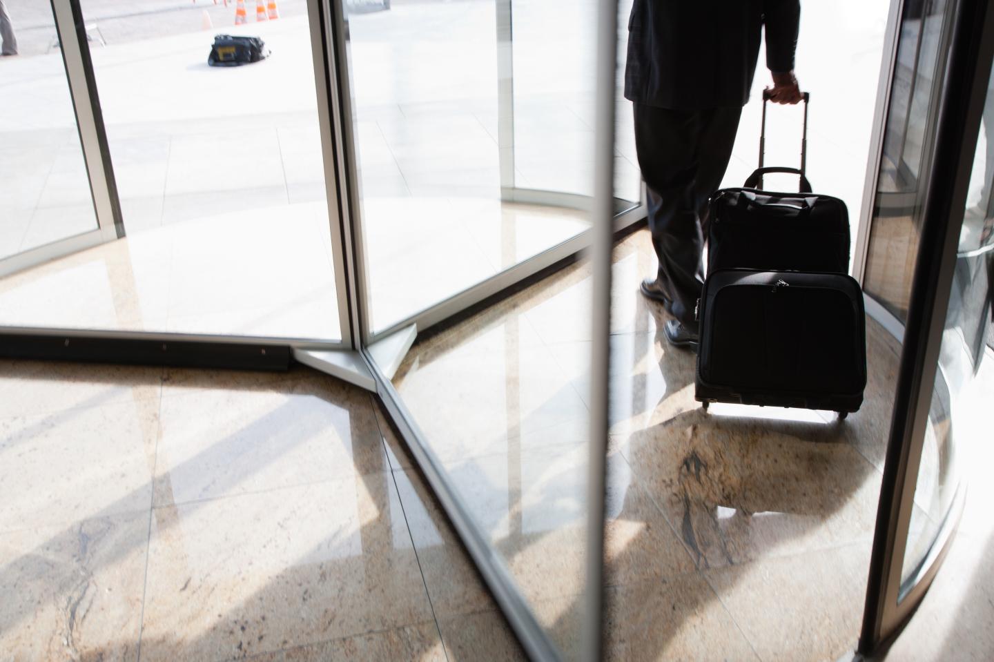 Businessman with suitcase using revolving door