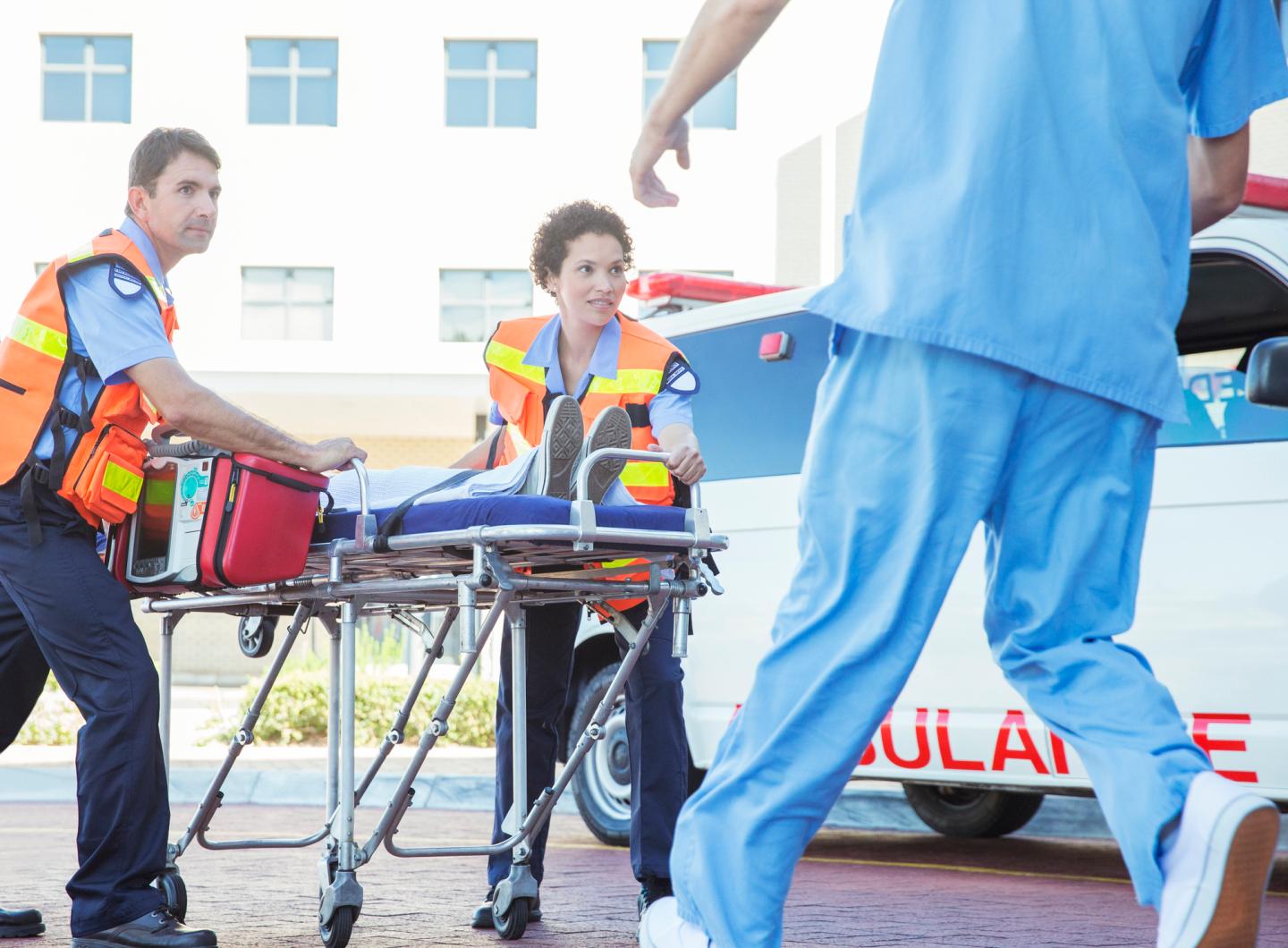 Paramedics wheeling patient in hospital parking lot