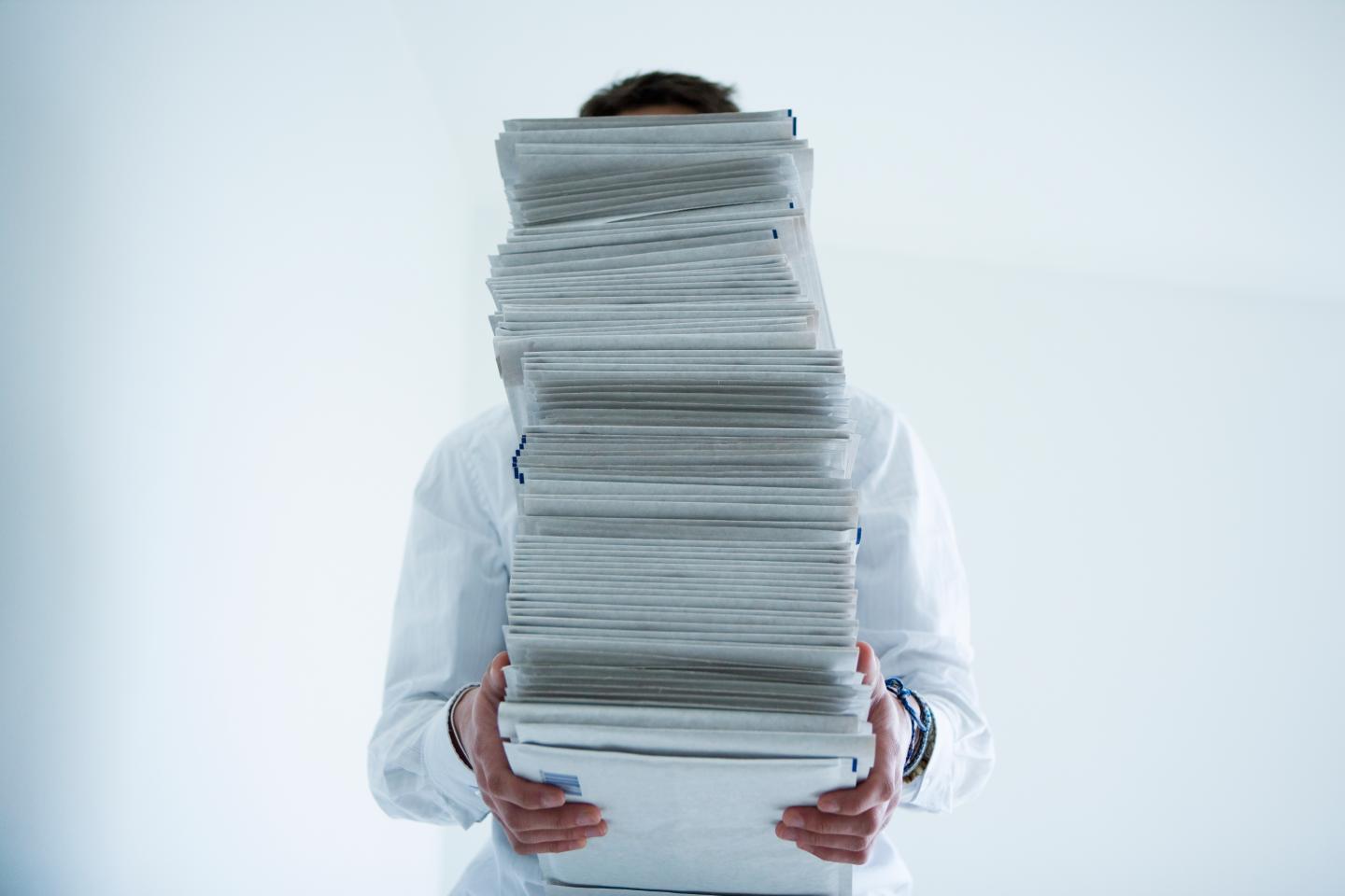 Man holding stack of paper in front of face