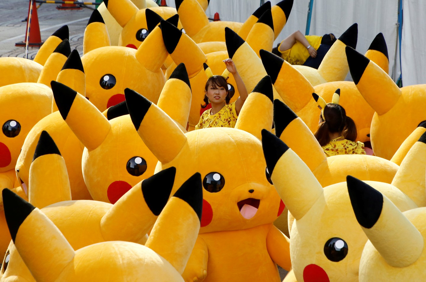A staff guides performers wearing Pokemon's character Pikachu costumes as they prepare for a parade in Yokohama