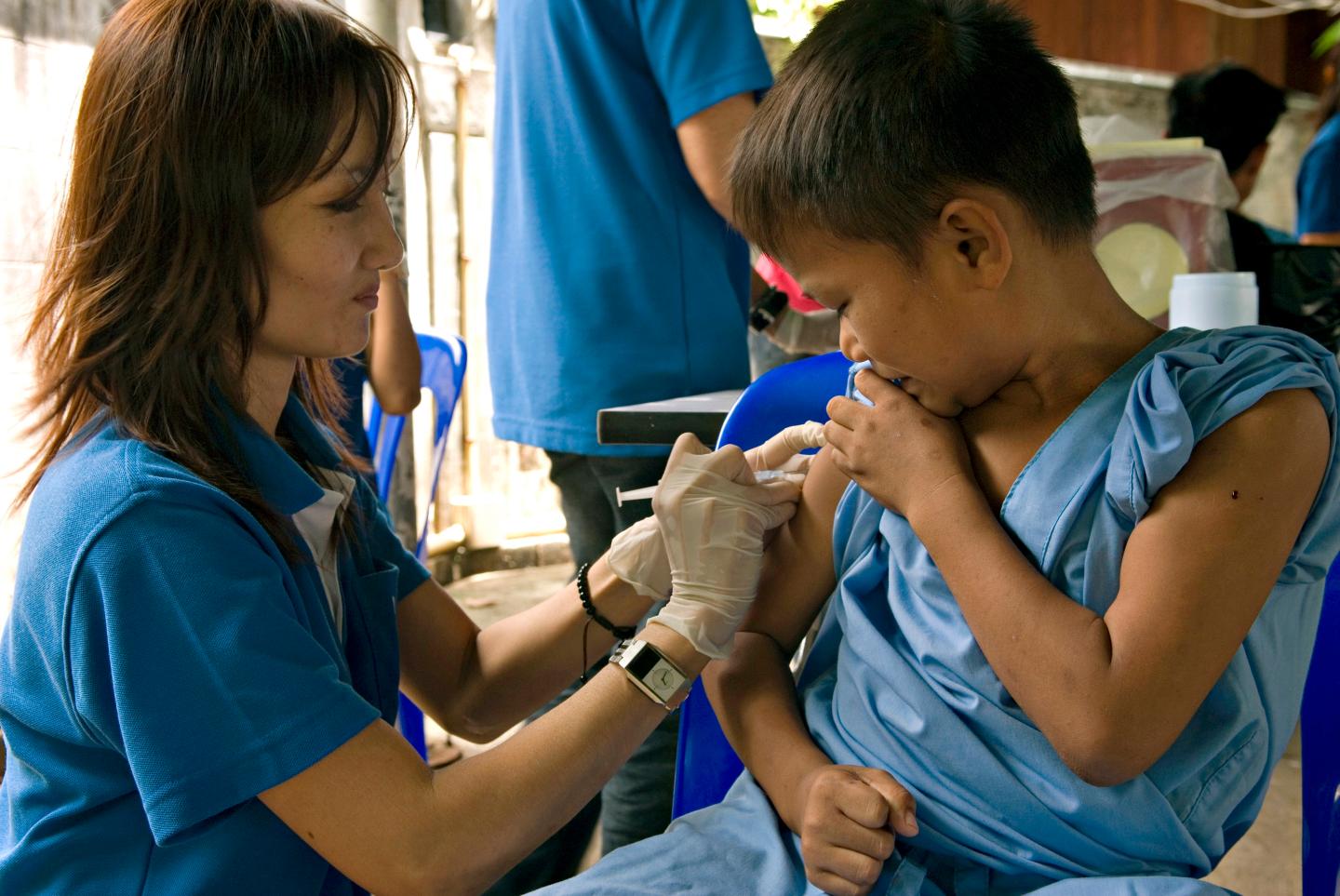 A nurse is vaccinating a young Burmese refugee candidate to