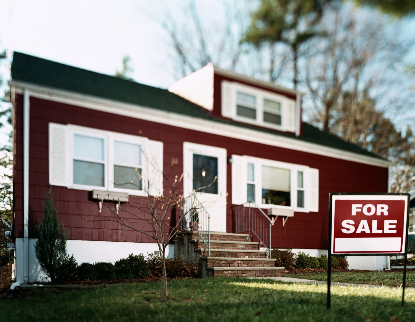 'For sale' sign on lawn in front of house