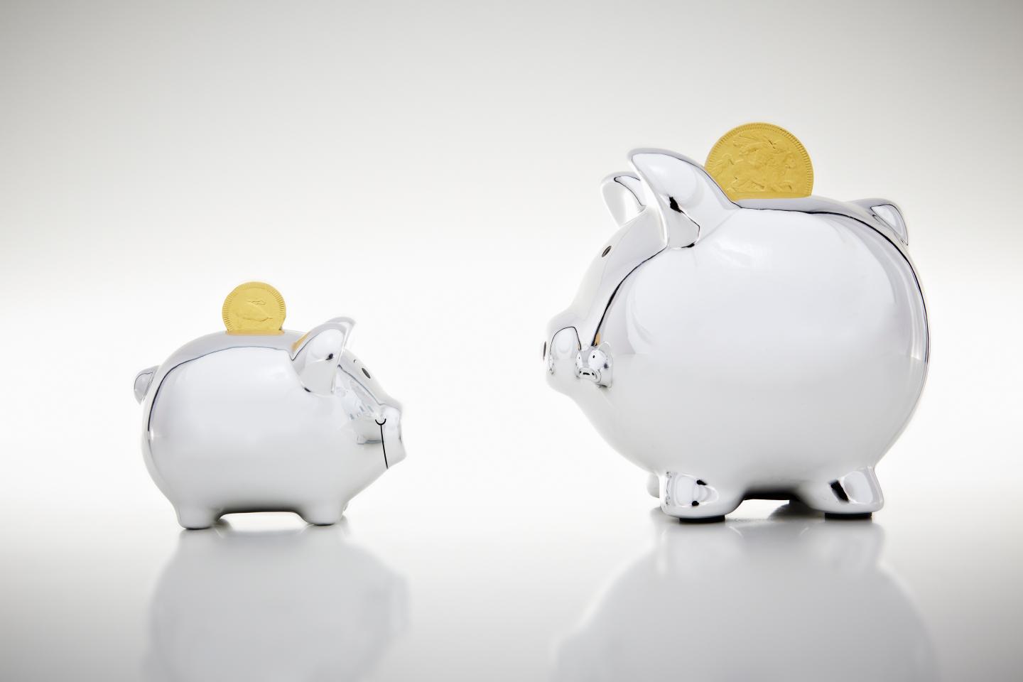 Gold coins dropping into piggy banks