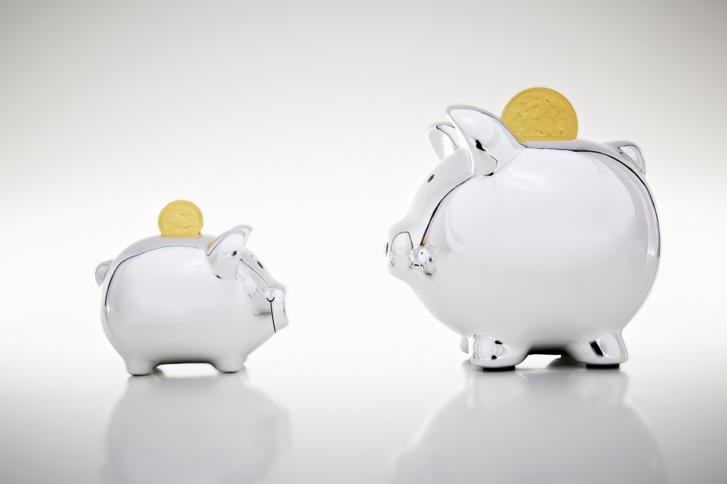 Gold coins dropping into piggy banks